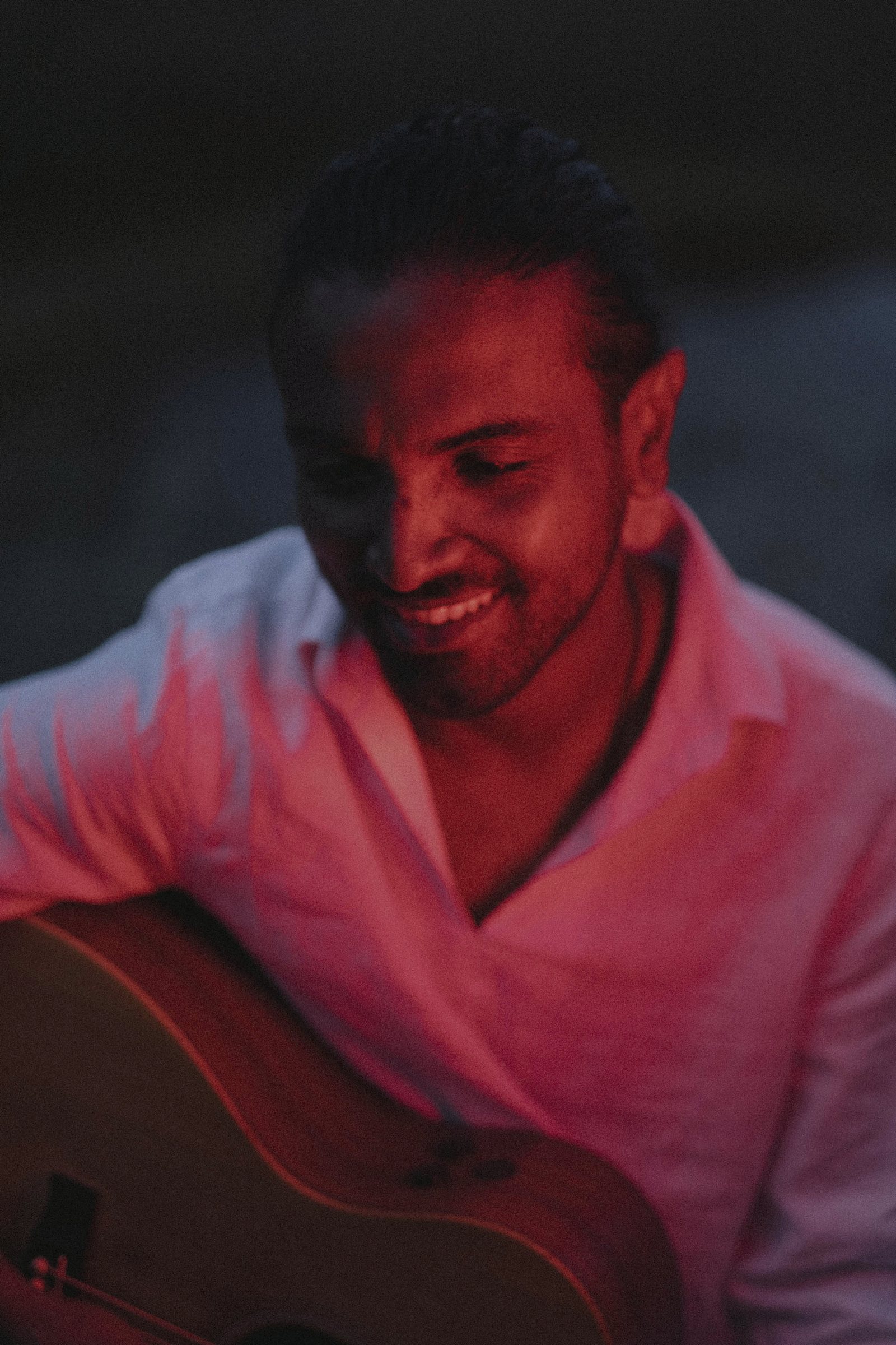 Lasith Fernando with an acoustic guitar, lit in red